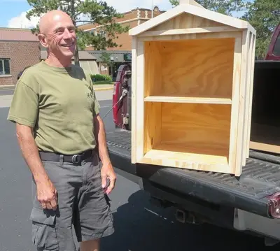 Claud stands next to Little Free Library in progress on pickup bed
