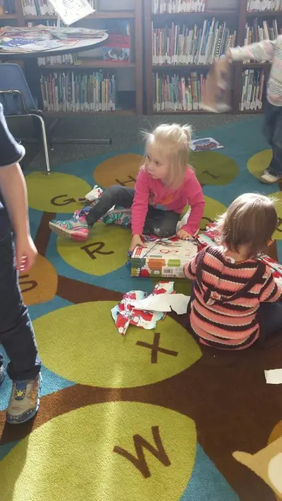 toddlers unwrapping gifts in the library