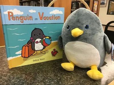 stuffed penguin next to the book "Penguin on Vacation"