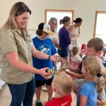 adult holds snake while children touch it