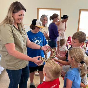 adult holds snake while children touch it