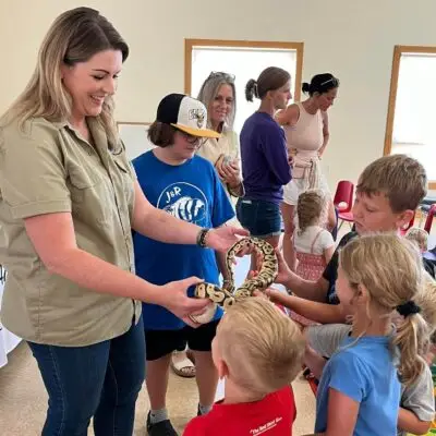 adult holds snake while children touch it