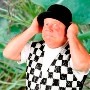 Jeff is holding his black hat on his head and wearing a black & white checkered vest