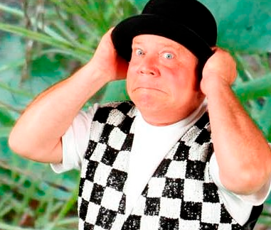Jeff is holding his black hat on his head and wearing a black & white checkered vest