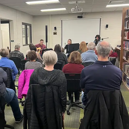 3-pc music group playing for seated audience in library