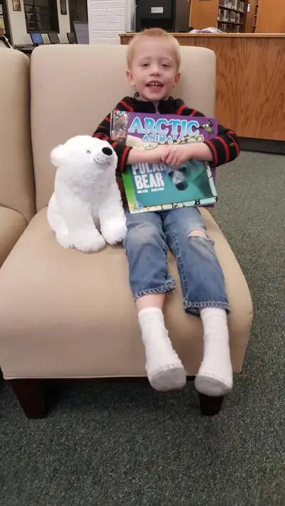 toddler on chair with stuffed polar bear and books about polar bears