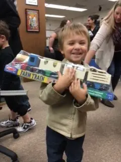 smilling child holding a toy farm train