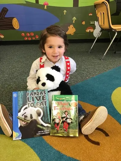 toddler with stuffed panda and books entitled "Pandas Live to Eat" and "Perfect Time for Pandas"