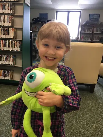 smiling toddler holding a stuffed monster