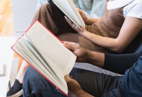 people sitting next to each other reading books